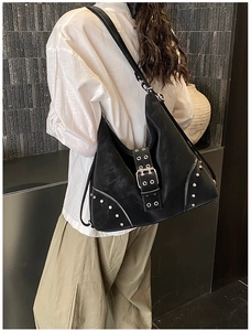 Detail of black rivets tote bag with silver studs and decorative zippers on industrial wall
