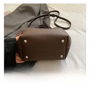 Détail du fond d'un sac en cuir marron foncé avec quatre pieds de protection en argent