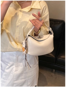 Close-up of cream textured leather handbag with metallic twist lock and cute rabbit charm