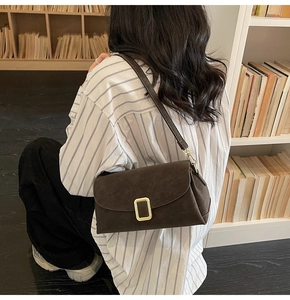 Sac bandoulière vintage marron foncé avec boucle dorée dans une scène de bibliothèque