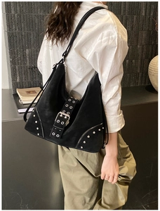 Detail of black suede tote bag with large eyelet buckle and silver rivet punk accents