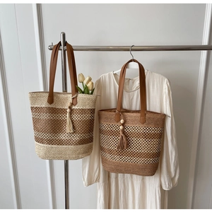 Close-up of woven straw tote bags with leather handles and decorative tassels