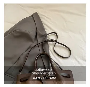 Détail du sac à main en cuir marron texturé avec bandoulière réglable et boucle décorative