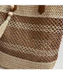 Detailed view of woven straw tote bag texture with brown leather handle and tassel