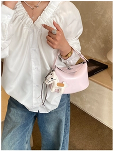 Detail of pink shoulder bag with polished texture and a white leather horse charm