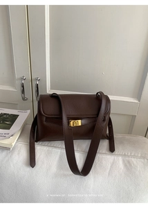 Détail d'un sac à bandoulière marron foncé vintage avec fermoir doré en forme d'arche évidée