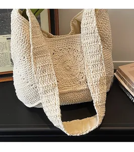 Détails des motifs en crochet et des bretelles sur un sac seau de plage beige tricoté