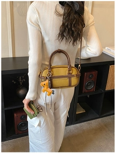 Detail einer gelben Boston-Tasche mit braunem Lederkontrast und Pferdeanhänger