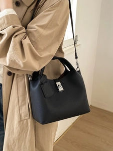 Chic black litchi pattern leather bucket bag with silver lock worn with a trench coat