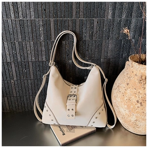 Detail of white leather Hobo bag with silver studs and decorative buckle on book