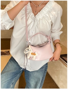 Detail view of pink textured leather handbag with a stylish horse charm on side