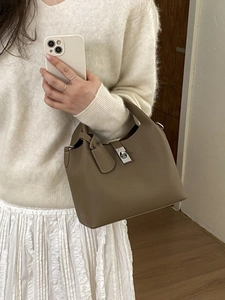 Elegant tan leather bucket bag with silver lock closure and subtle litchi texture