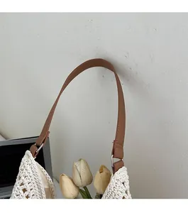 Detailed close-up of brown faux leather strap on white hand-knitted crochet tote bag