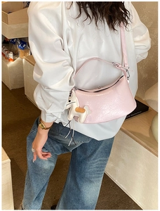 Detail of pink crescent bag featuring glossy cracked leather and a horse charm