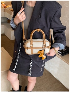 Detail einer Boston-Tasche mit beigem Lychee-Leder und einem hundeförmigen Anhänger