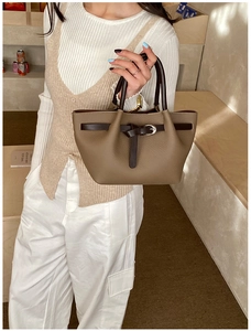 Détail d'un sac cabas trapèze en cuir marron avec boucle argentée et texture grainée fine