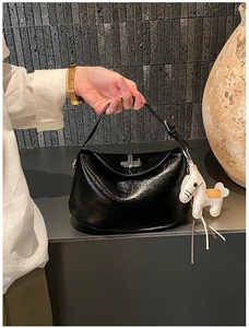 Detail view of black glossy leather handbag with silver clasp and white pony charm