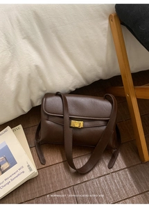 Détail de sac bandoulière rétro en cuir marron foncé avec fermoir rotatif doré minimaliste