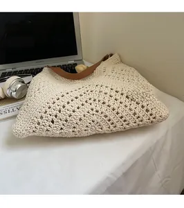 Detail of hand-woven cream tote bag featuring brown leather straps and metallic rings