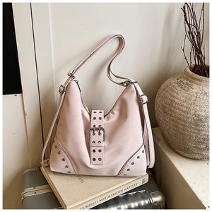 Detailed close-up of pink hobo bag with silver rivets and metal buckle on suitcase