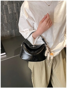 Detail of black glossy leather handbag with metal buckle and white pony charm