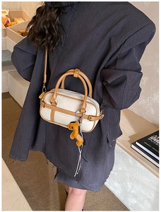 Detailaufnahme der kleinen Boston Bag in Kontrastfarben mit cremefarbener Textur und Lederbesatz