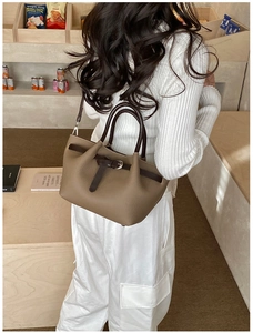 Détail d'un sac à main en cuir marron à motif litchi avec anses sombres et boucle en métal