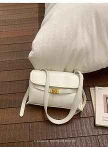 Gros plan d'un sac à bandoulière en cuir blanc vintage avec fermoir rotatif doré élégant