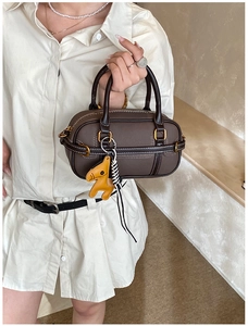 Detail der dunkelbraunen Boston Bag mit weißen Kontrastnähten und gelbem Pferdeanhänger