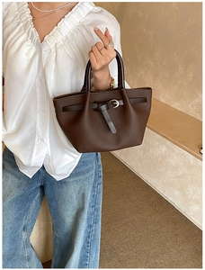 Gros plan sur un sac cabas marron vintage montrant la texture grainée et la boucle argentée