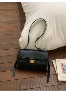 Gros plan d'un sac à bandoulière rétro noir avec fermoir tournant en métal doré gravé