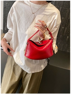 Close-up of red glossy leather handbag featuring natural creases and a cute cat charm