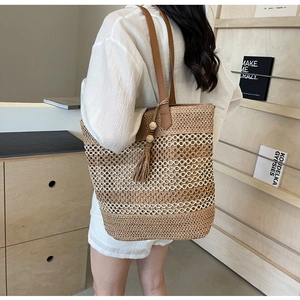 Close-up of color-block straw tote bag with leather straps and tassel detail