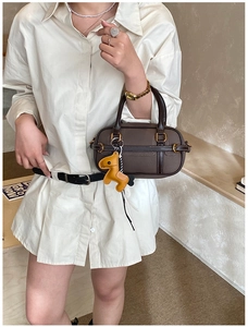 Detail der Boston Bag mit strukturierter Lederoptik und gelbem Pferdeanhänger Dekor