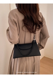 Minimalist black lychee leather bag worn by model showing retro crossbody style