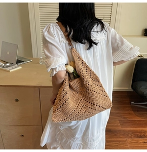 Detail of woven straw tote bag with brown leather straps and hollow knit texture