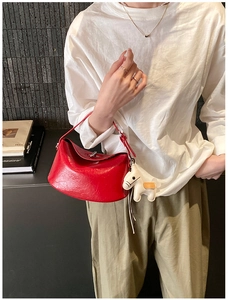Detail of red leather Lindy style handbag with metal clasp and white horse charm