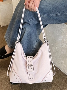 Chic pink oversized rivet tote bag with buckle details shown in a lifestyle street setting
