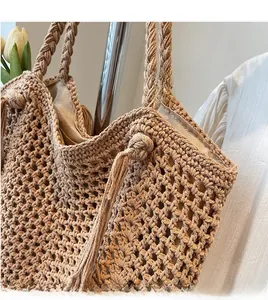 Gros plan d'un sac cabas en paille avec des anses tricotées et détails de pompons