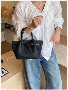 Détail du sac cabas en cuir noir grainé avec sangles à boucle et esthétique minimaliste