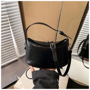 Detail of glossy black crescent shoulder bag with silver clasp and adjustable strap