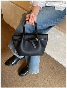 Détail du sac à main noir en cuir grainé avec poignée ronde et boucle en métal dorée