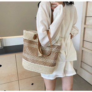 Detail of contrast woven straw tote bag with brown leather straps and tassels