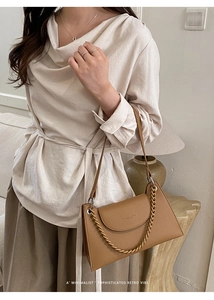 Detail of camel lychee leather shoulder bag with decorative gold chain and trapezoid shape