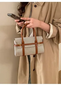 Dettagli in tela beige e cuciture in pelle marrone su una borsa a tracolla elegante