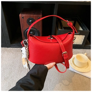 Macro detail of red faux leather handbag with fine grain texture and white animal charm
