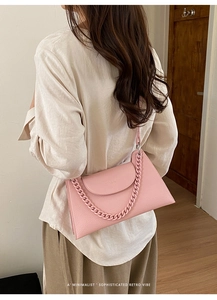 Detail of pink lychee leather handbag with chunky chain strap on a model shoulder