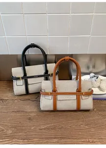 Dettaglio di borsa minimalista in tela con finiture in pelle e fibbia in metallo oro