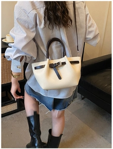 Gros plan d'un sac à main en cuir beige texturé avec poignées marron et boucle décorative