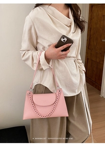 Detail of pink pebbled leather handbag with decorative thick chain and embossed logo